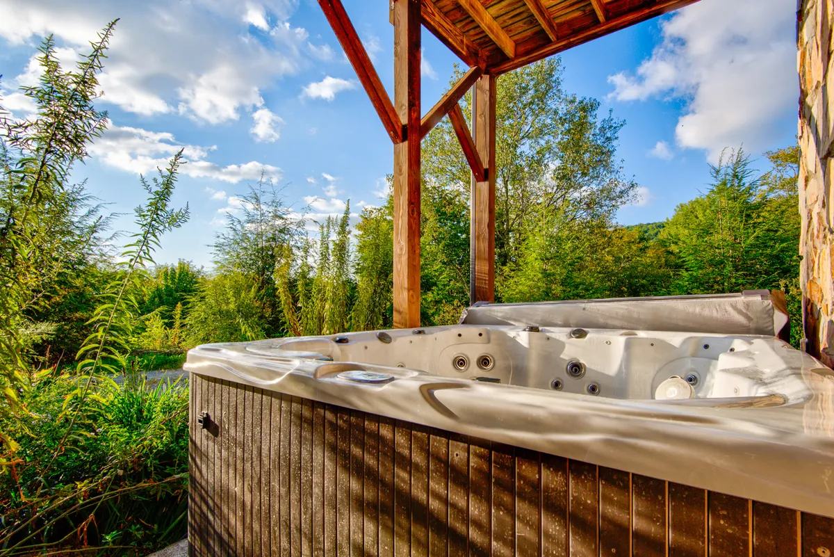 This image showcases an inviting outdoor hot tub nestled against a wooden structure, surrounded by lush greenery. The setting exudes privacy and relaxation, perfect for unwinding after a day of mountain adventures. The hot tub is the central focus, inviting guests to imagine soaking under the stars.
