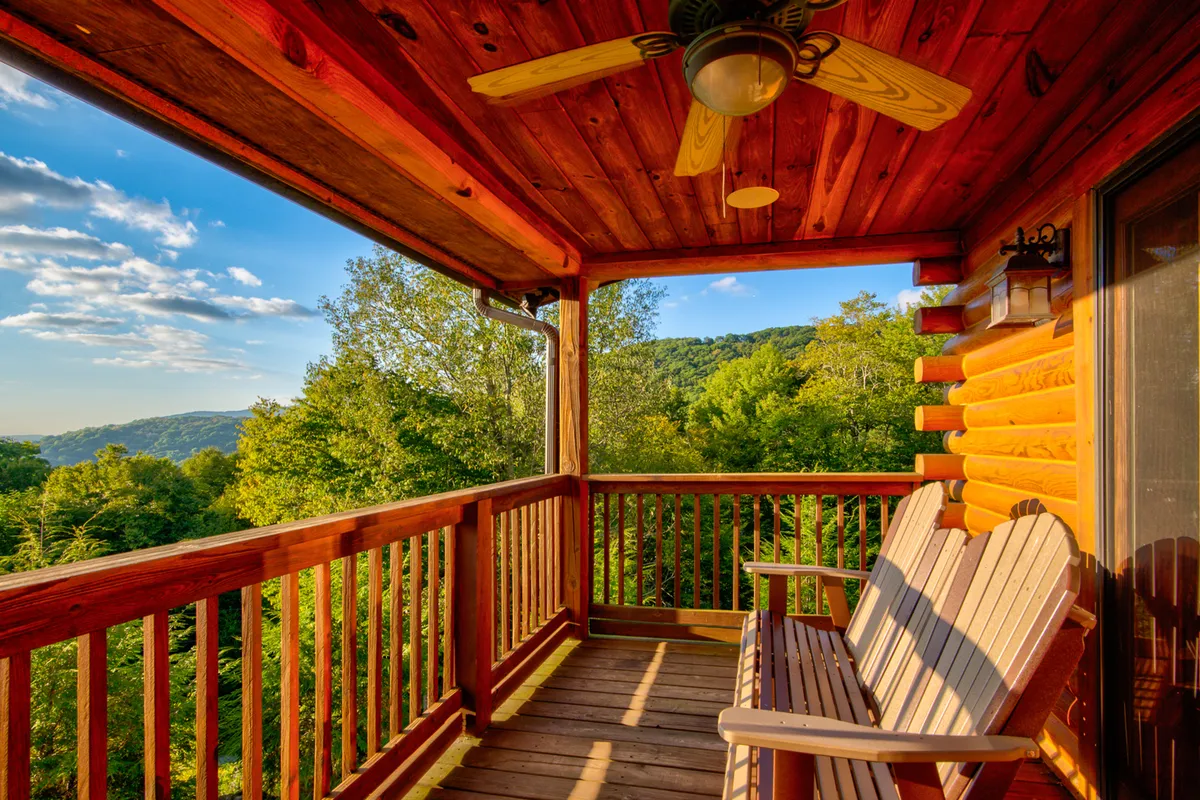 A pair of wooden rocking chairs face a breathtaking mountain vista beneath a sunset sky. The tranquil exterior setting hints at the peaceful, private yard and invites moments of relaxation, reflection, or sharing stories as dusk settles.