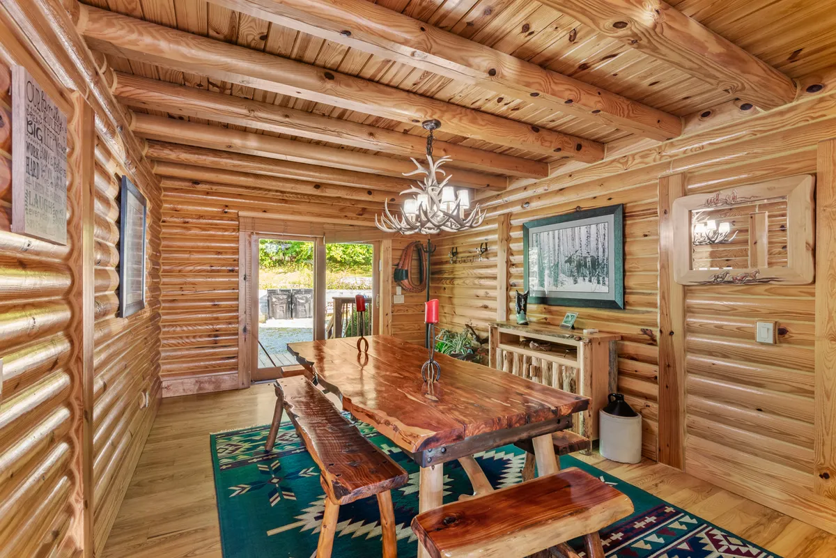 A beautifully rustic dining room with a large wooden table under a striking chandelier, surrounded by log cabin walls and vibrant artwork. The setting is perfect for group dinners or festive family meals, echoing the text's mention of memorable gatherings.