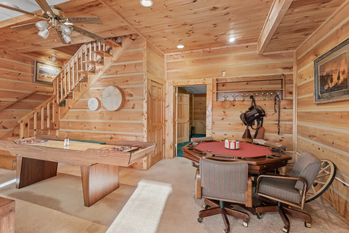 Featuring both a pool table and a dedicated poker table, this image highlights the playful and social atmosphere of Sugar Bear Lodge’s entertainment spaces. Framed artwork and the wooden staircase add warmth and personality to the scene.