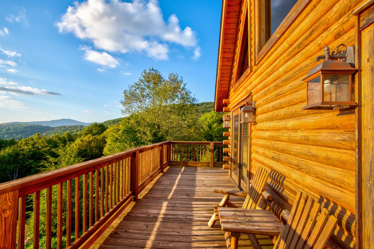 A wooden deck stretches out from the log cabin, outfitted with rocking chairs and lanterns, offering sweeping views of the mountains and sky. The setting is tranquil—ideal for morning coffee or starlit gatherings with loved ones.